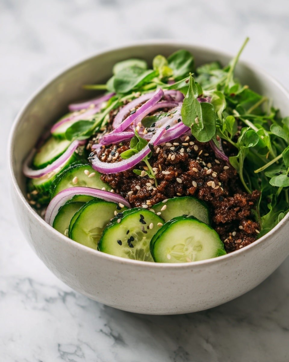 A white bowl filled with a layered salad that starts with a base of dark brown minced meat, topped with bright green cucumber slices that have a fresh, shiny texture, scattered thin curved strips of purple-red onion, and sprinkled with fresh green leafy herbs and black and white sesame seeds. The ingredients look vibrant and fresh, set against a white marbled surface. Photo taken with an iphone --ar 4:5 --v 7 — Spicy Korean Ground Beef with Cucumber Salad, Korean-inspired ground beef recipe, quick Korean ground beef dinner, easy Korean beef stir-fry, healthy beef and cucumber salad